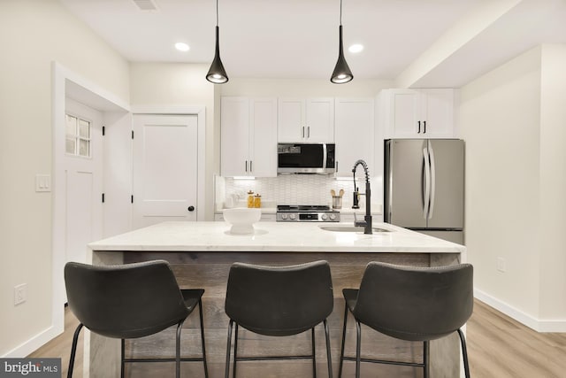 kitchen featuring stainless steel appliances, white cabinetry, light stone counters, and decorative backsplash