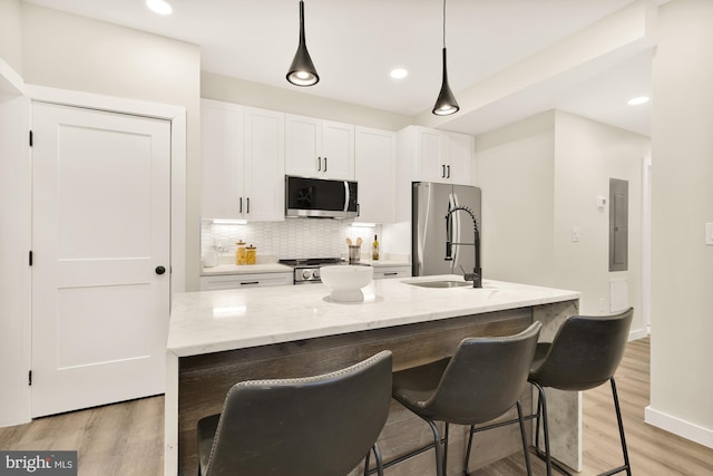 kitchen with stainless steel appliances, light wood-type flooring, white cabinetry, and decorative backsplash