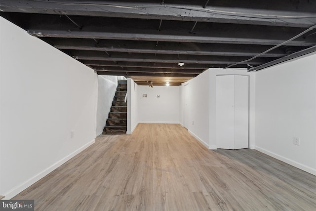 finished below grade area with stairway, baseboards, and wood finished floors