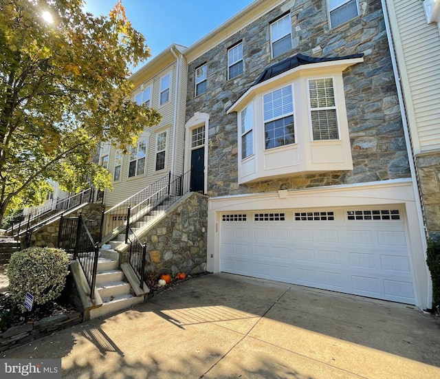 view of property featuring a garage, stone siding, and driveway