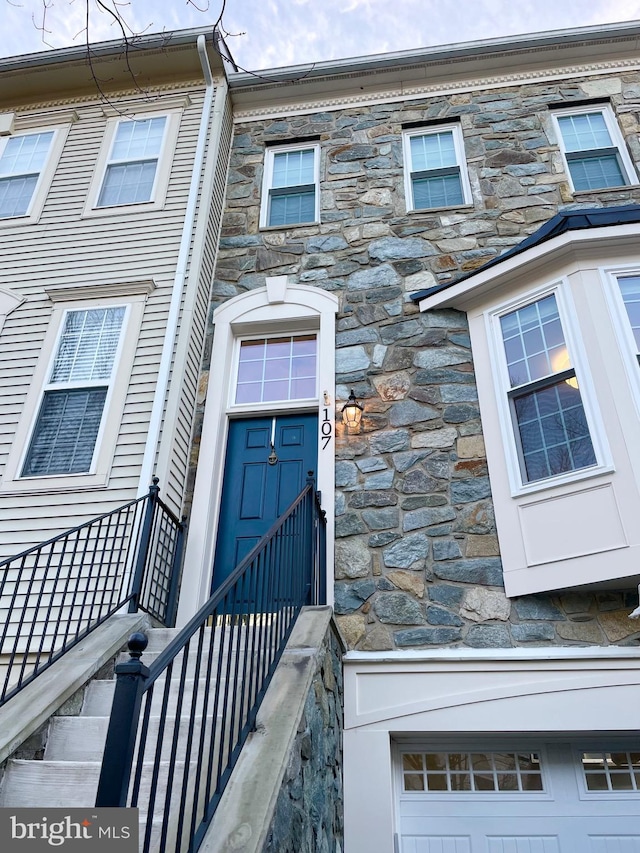 doorway to property featuring a garage and stone siding