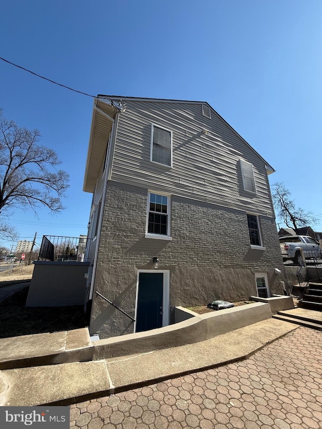 back of house with brick siding and fence