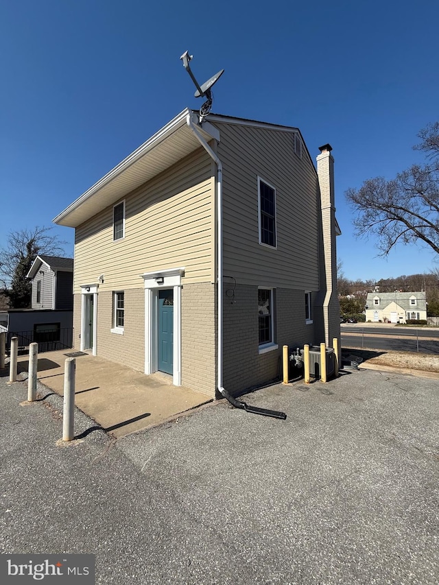 back of property with a chimney and brick siding