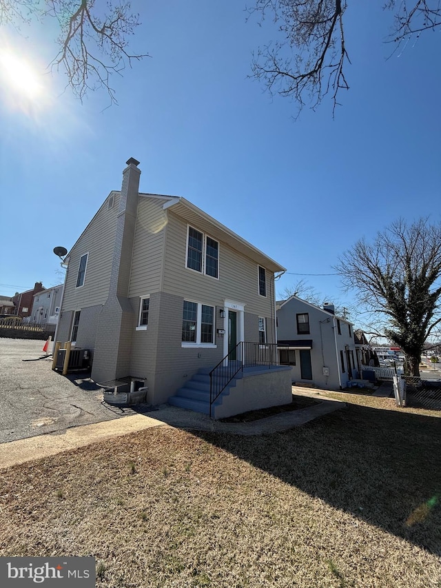 back of property featuring cooling unit, brick siding, and a chimney