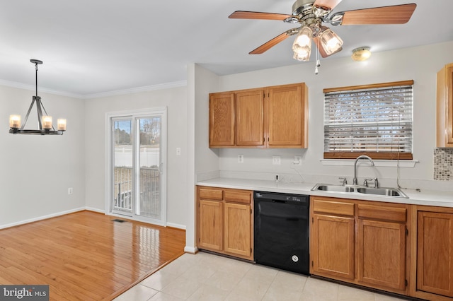 kitchen featuring black dishwasher, light countertops, crown molding, pendant lighting, and a sink