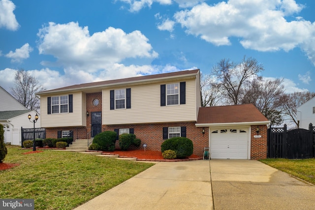 raised ranch featuring a garage, driveway, a front lawn, and brick siding