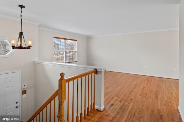 corridor featuring a chandelier, light wood-style flooring, an upstairs landing, baseboards, and ornamental molding