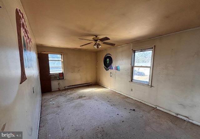 unfurnished room with a baseboard heating unit, ceiling fan, and cooling unit