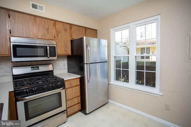 kitchen featuring tasteful backsplash, baseboards, visible vents, stainless steel appliances, and light countertops