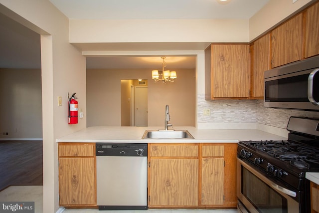 kitchen featuring a chandelier, stainless steel appliances, a sink, light countertops, and backsplash