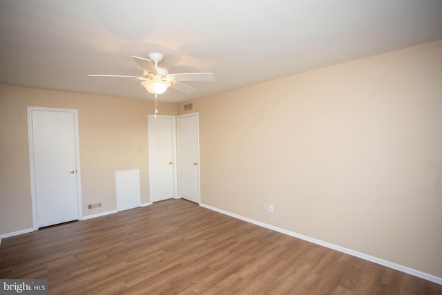 unfurnished bedroom featuring a ceiling fan, baseboards, visible vents, and wood finished floors