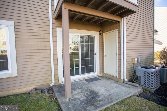 view of exterior entry with a patio and central air condition unit