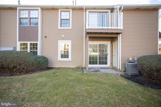 rear view of house featuring central AC, a lawn, and a balcony