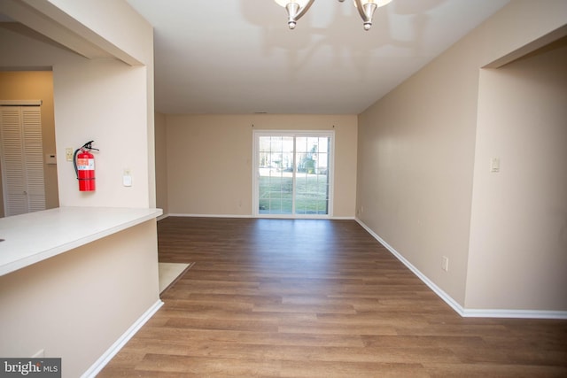 interior space featuring an inviting chandelier, baseboards, and wood finished floors