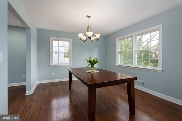 unfurnished dining area with dark wood-style flooring, visible vents, a notable chandelier, and baseboards