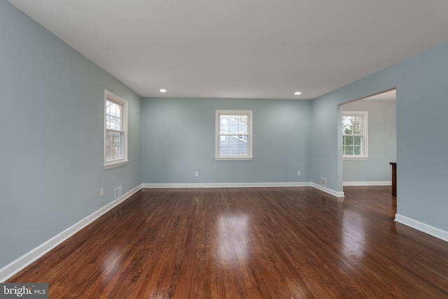 empty room with dark wood-style floors, visible vents, baseboards, and recessed lighting