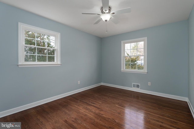 unfurnished room with a ceiling fan, dark wood finished floors, visible vents, and baseboards