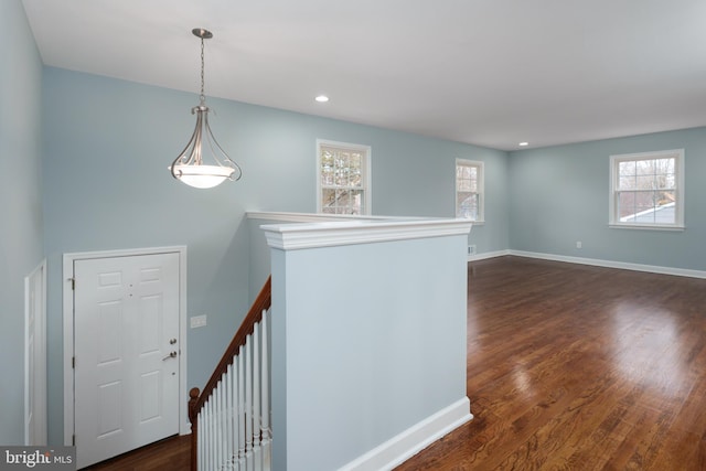 interior space featuring recessed lighting, dark wood-style flooring, baseboards, and an upstairs landing