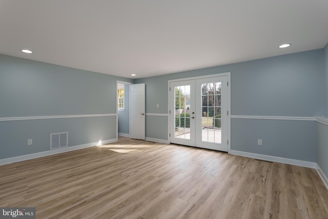 unfurnished room with light wood-style floors, baseboards, visible vents, and french doors