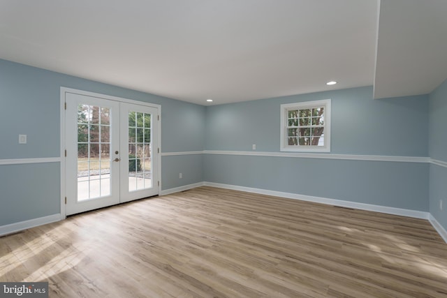 unfurnished room with baseboards, wood finished floors, a wealth of natural light, and french doors