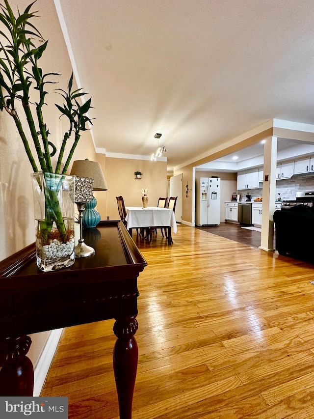 dining room with light wood-style floors, baseboards, and ornamental molding