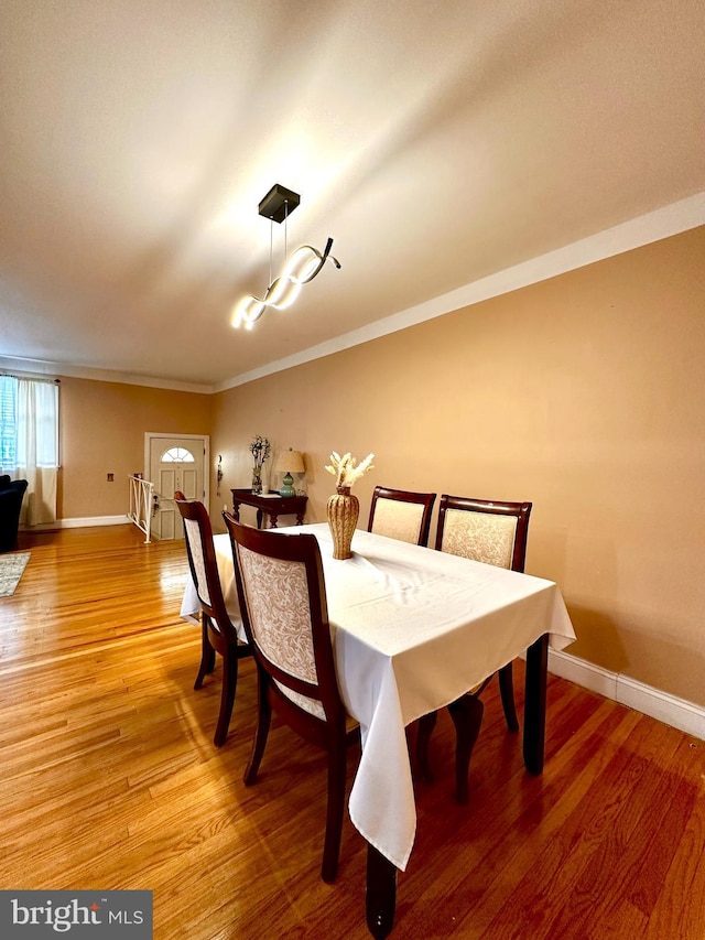 dining room with light wood-style floors, crown molding, and baseboards