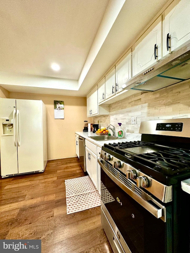 kitchen featuring stainless steel appliances, a sink, white cabinets, and under cabinet range hood