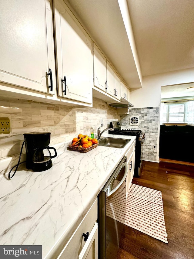 kitchen featuring dark wood-style floors, stainless steel appliances, white cabinets, a sink, and light stone countertops