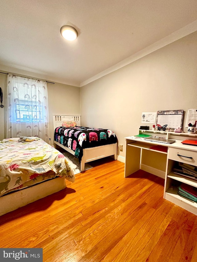 bedroom with ornamental molding and light wood-style flooring