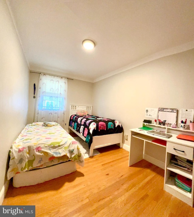 bedroom with light wood-style flooring, ornamental molding, and baseboards