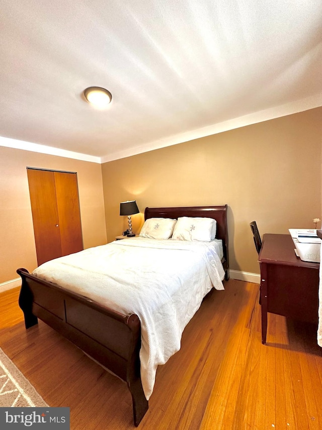 bedroom with a closet, baseboards, and wood finished floors