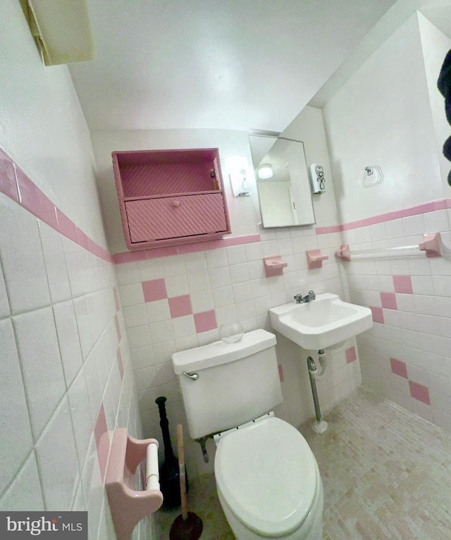 half bath featuring a wainscoted wall, toilet, and tile walls