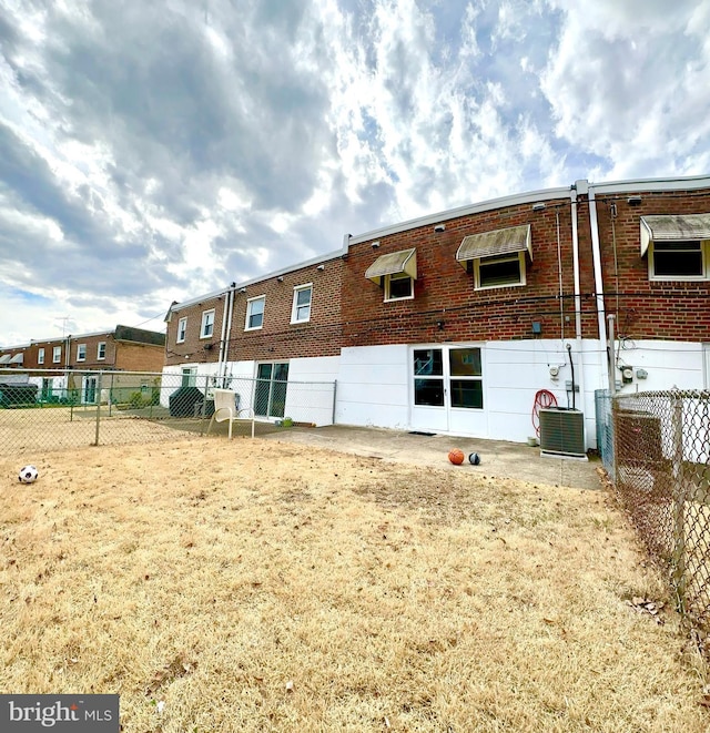 rear view of house featuring brick siding and fence