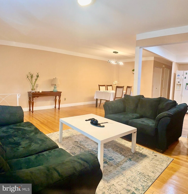 living room featuring ornamental molding, light wood-style flooring, and baseboards