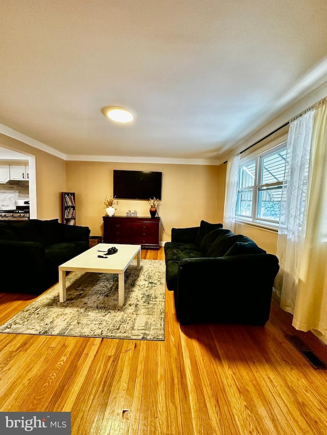 living room featuring ornamental molding, visible vents, and wood finished floors