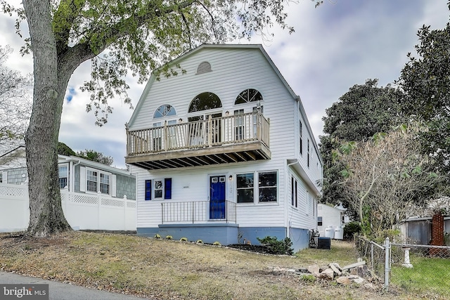 view of front of home with a balcony, covered porch, fence, and a gambrel roof