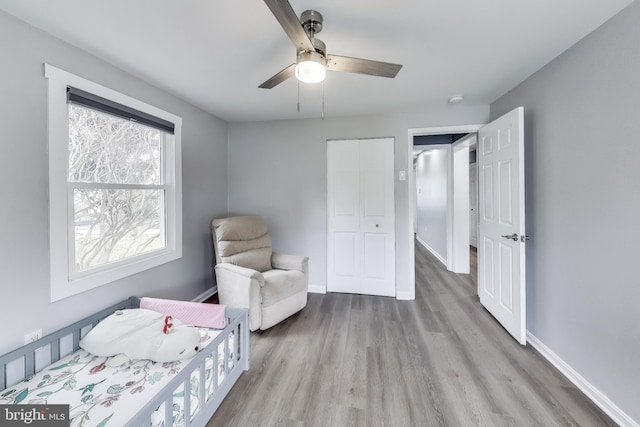 bedroom with ceiling fan, a closet, wood finished floors, and baseboards