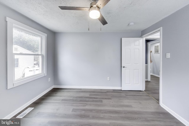 spare room featuring visible vents, a textured ceiling, baseboards, and wood finished floors