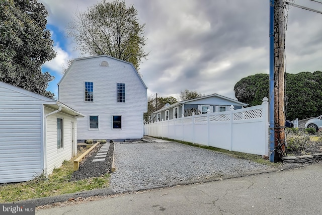 view of property exterior featuring fence and a gambrel roof