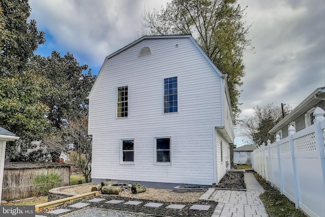 back of property with fence and a gambrel roof