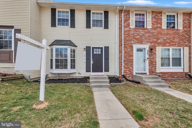 townhome / multi-family property featuring brick siding and a front yard