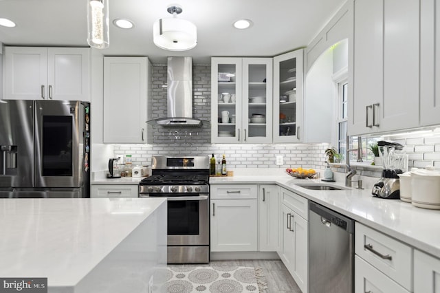 kitchen with appliances with stainless steel finishes, white cabinets, wall chimney range hood, and decorative backsplash