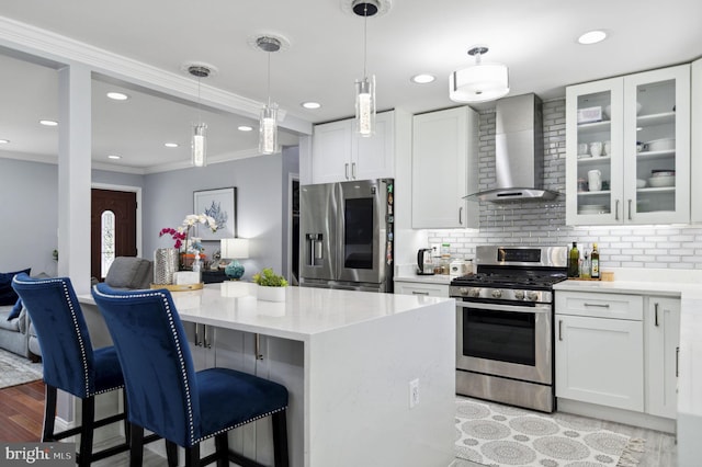 kitchen featuring ornamental molding, stainless steel appliances, wall chimney range hood, and backsplash