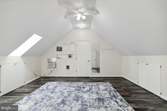 additional living space featuring ceiling fan, an AC wall unit, lofted ceiling with skylight, and dark wood-style flooring