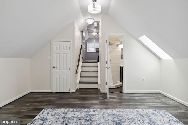 bonus room featuring vaulted ceiling with skylight, stairs, baseboards, and wood finished floors