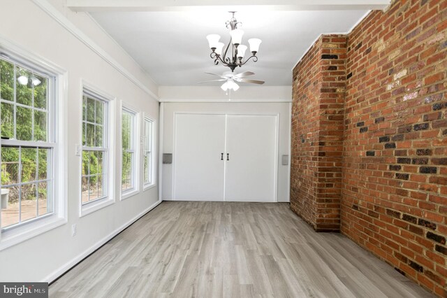 foyer entrance with brick wall, light wood finished floors, and a notable chandelier