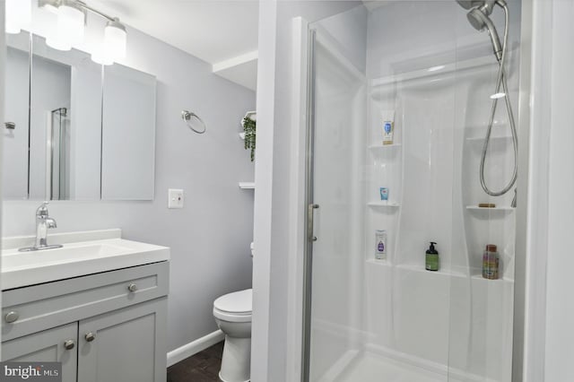 bathroom with toilet, a stall shower, and vanity