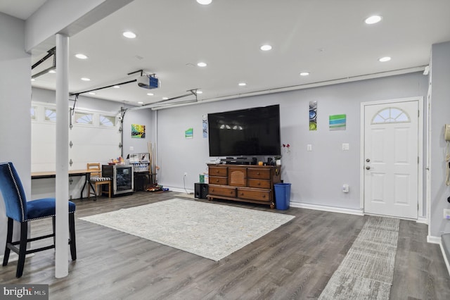 living area featuring a garage, baseboards, wood finished floors, and recessed lighting