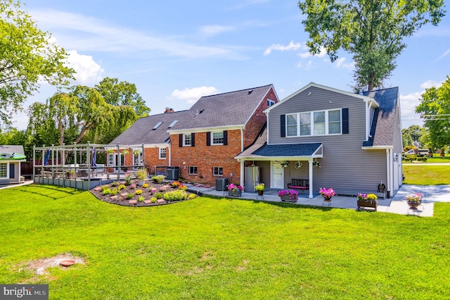 back of property featuring a shingled roof, cooling unit, and a lawn