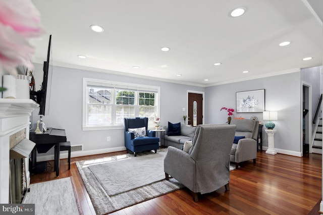 living area featuring ornamental molding, a tiled fireplace, and wood finished floors